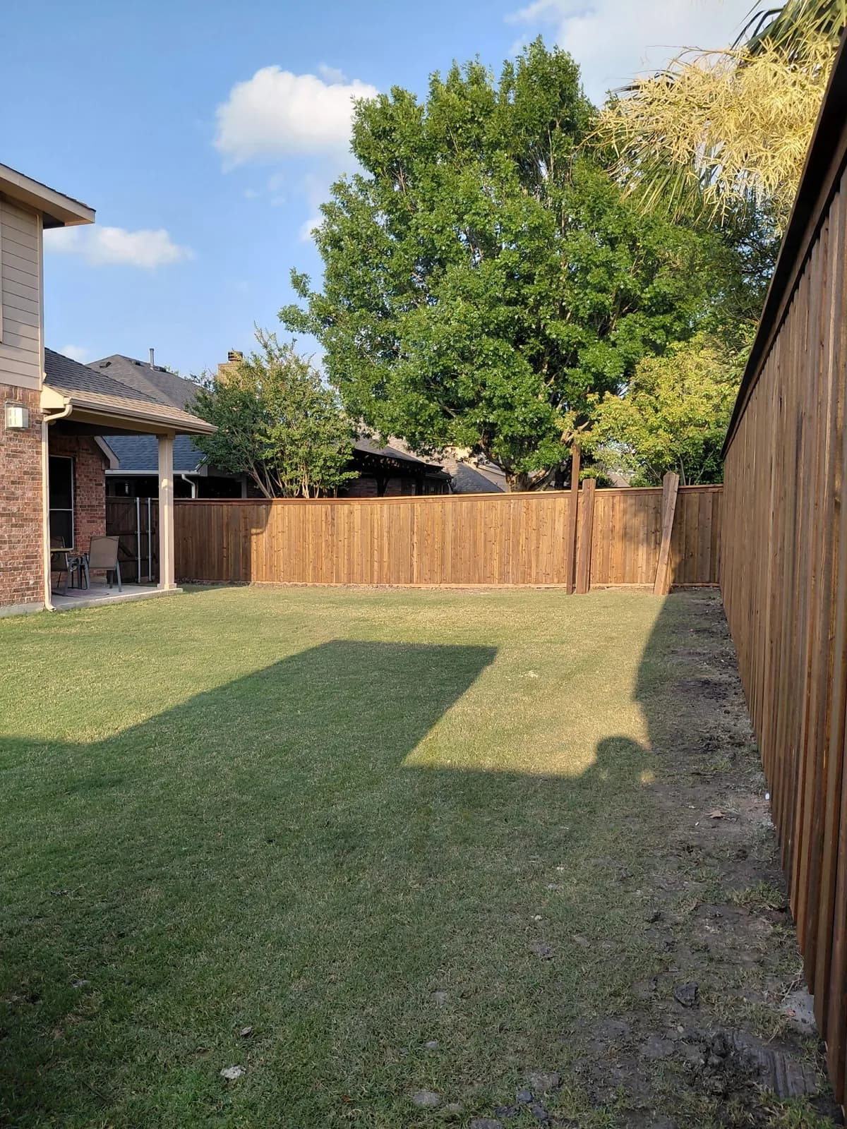 Cedar privacy fence around the back yard of a brick home.