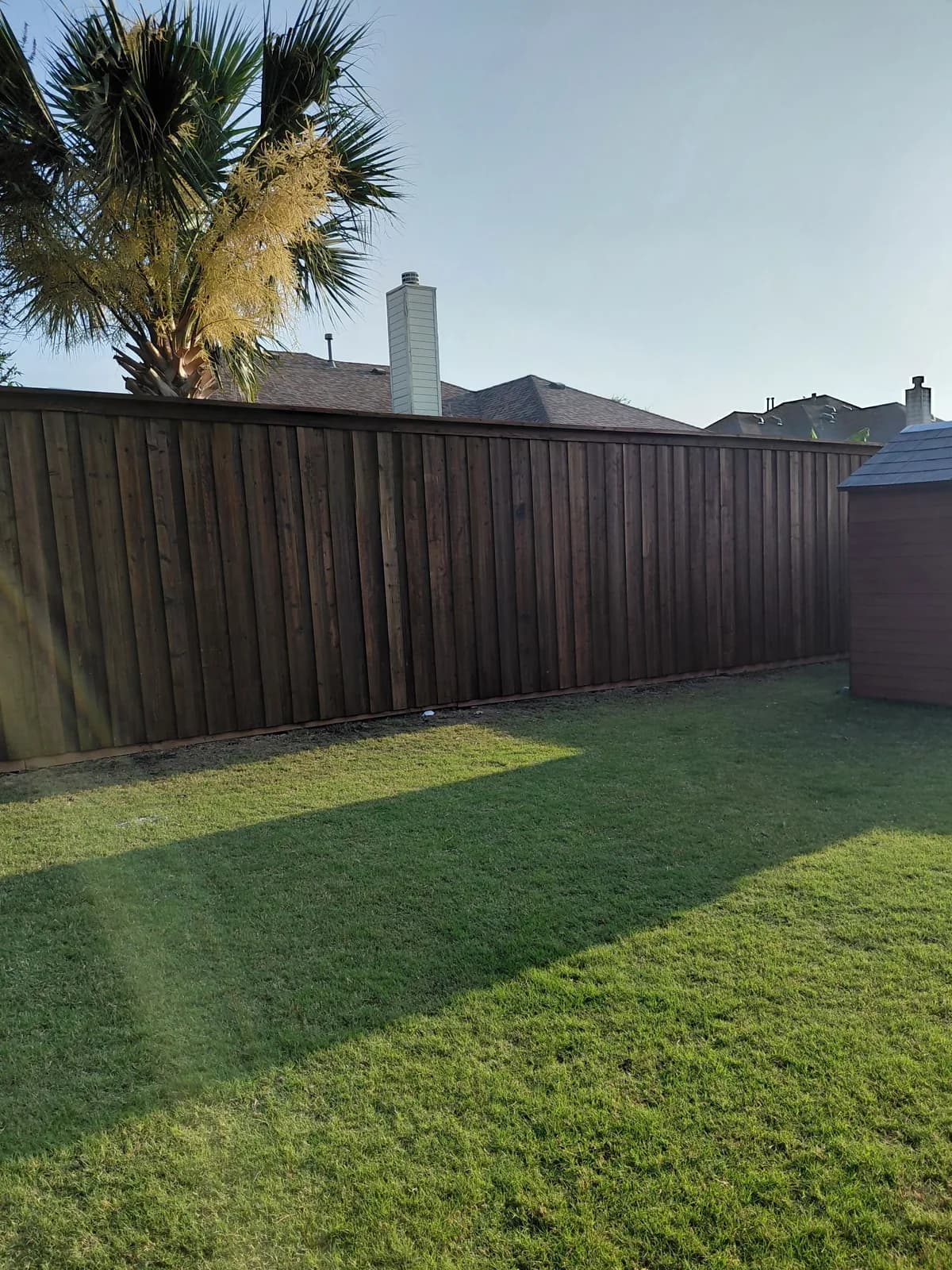 Dark-stained cedar privacy fence enclosing a back yard.