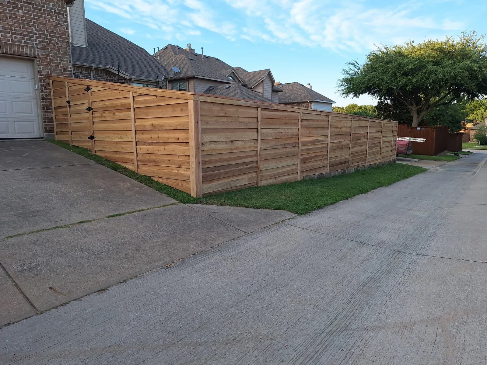 Horizontal cedar fence and matching gate along a driveway.
